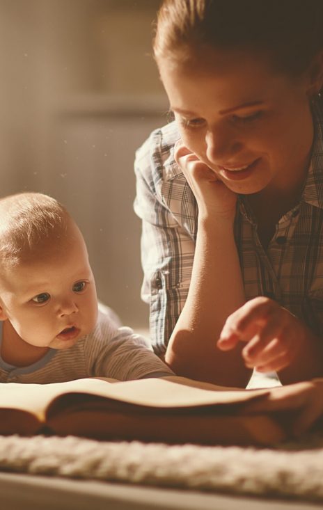 happy family mother and children read a book in the evening at home