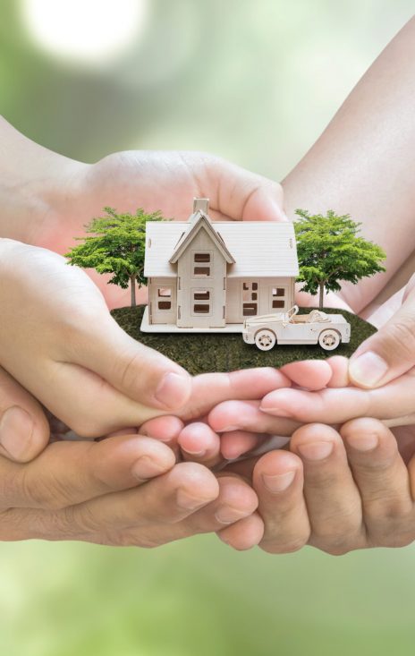 Safe family house model and garden on son daughter children kid guardian mother father hands, blur natural greenery tree planting environment background: Home loan property ownership assurance concept