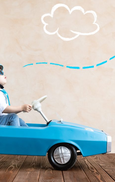 Happy child playing at home. Funny kid driving toy car indoor. Success and win concept