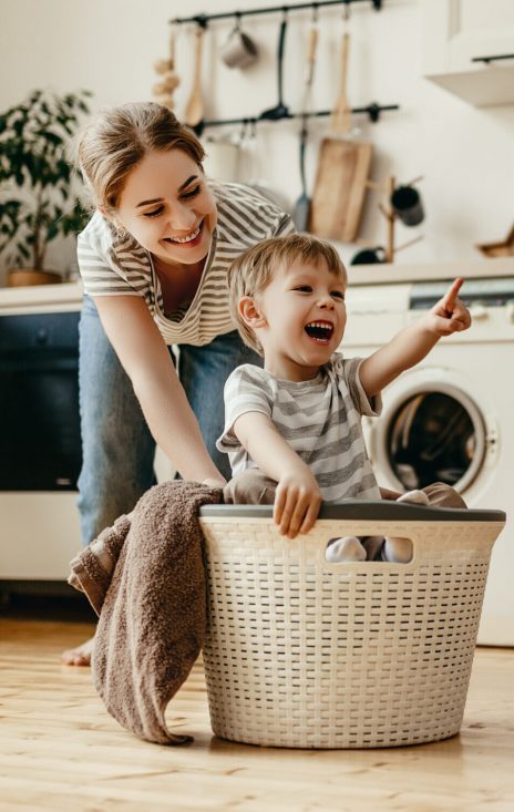 Happy family mother housewife and child son in laundry with washing machine