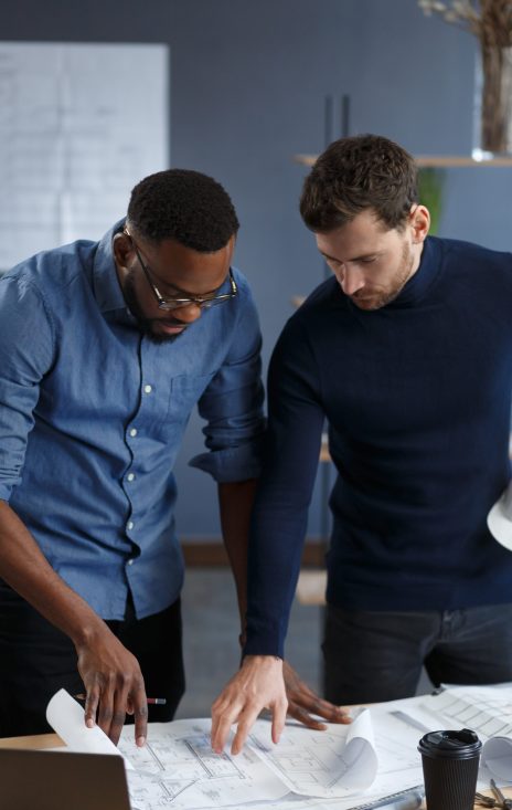 Multiracial engineer team working in office with blue prints and architect equipment sketching,discussing and planning construction project. Partners disputing at work. Business construction concept.